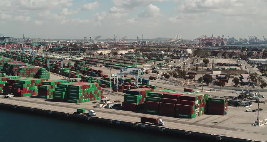 A shipping yard with containers and trucks with the sky and clouds in the background