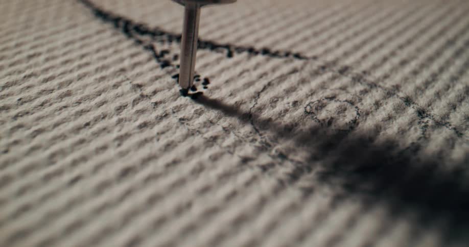 Black paint is quickly dotted on a canvas over and over to create a design