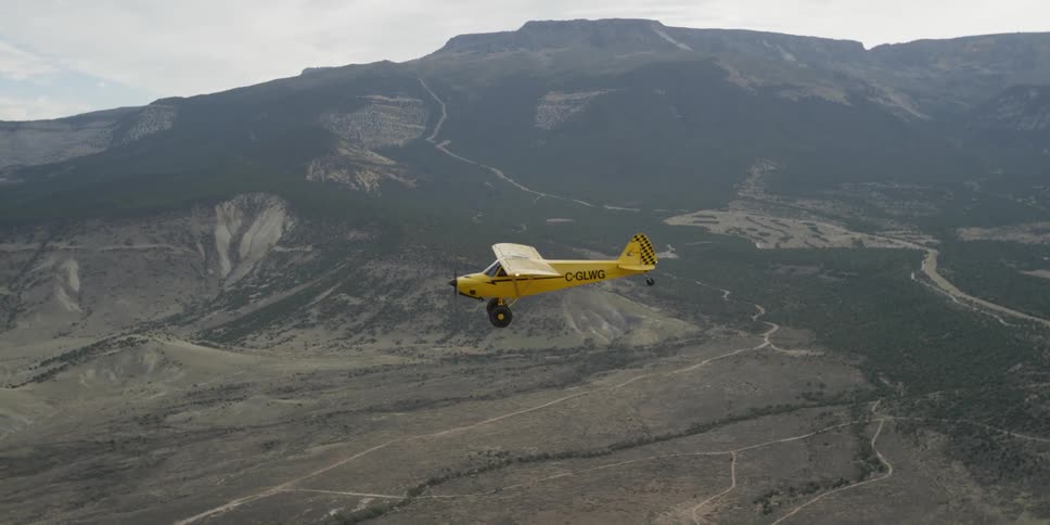 A yellow plane is flying in the sky