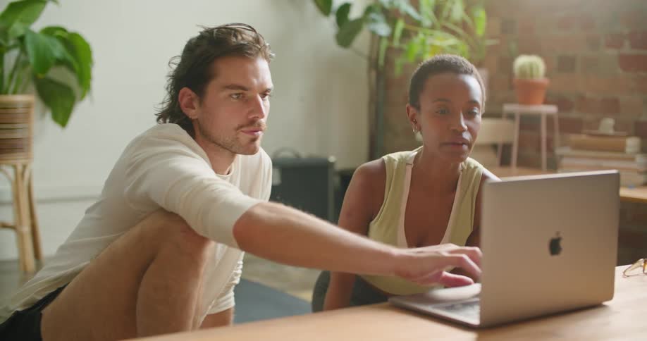 Young couple sitting on the floor in the living room using a laptop