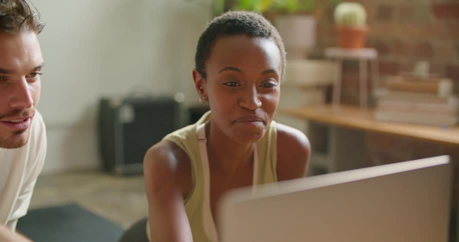 A man and woman laugh as they look at a computer screen