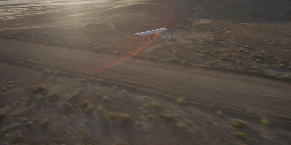 A plane takes off on a dirt runway