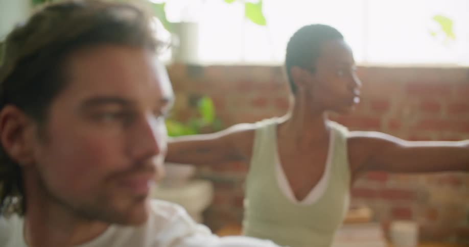 A man and woman stretch with their arms out in a yoga pose