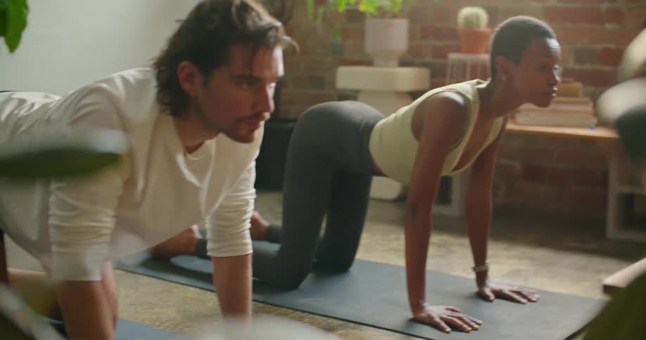 A man and woman do yoga at home