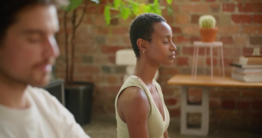 A man and woman sit on the floor while maintaining a meditative yoga pose