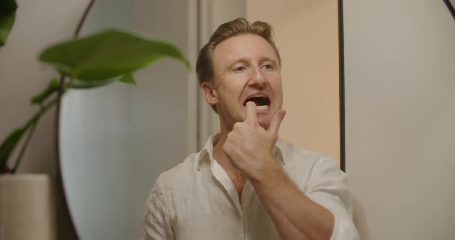 A man cleaning his teeth in front of a mirror