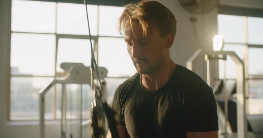 A man is working out in a gym next to a window