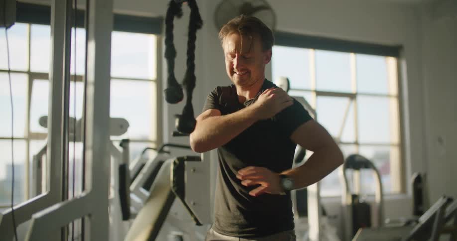A man winces as he holds his injured shoulder