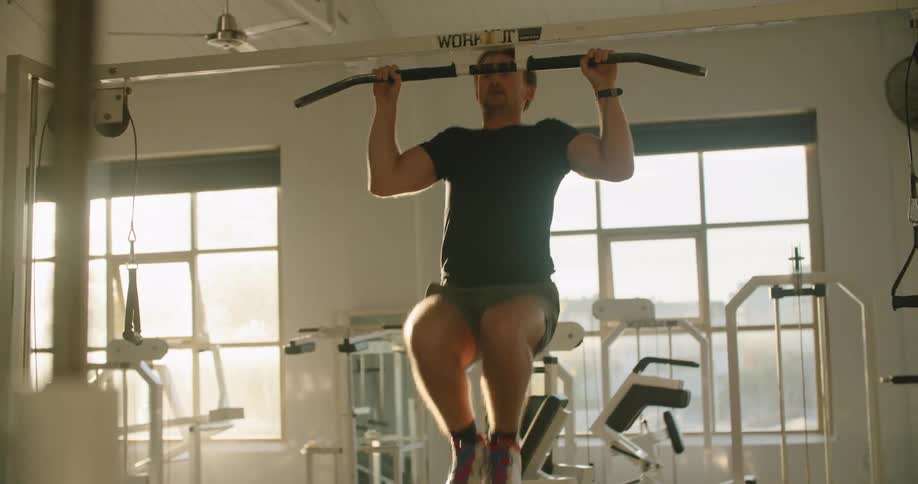 A man doing pull ups in a gym during the day