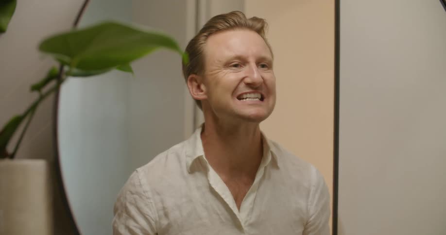 A man putting in a retainer in front of a mirror