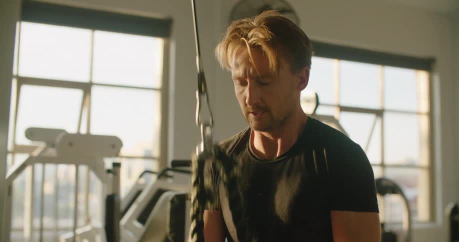 A man is working out in an empty gym at dusk