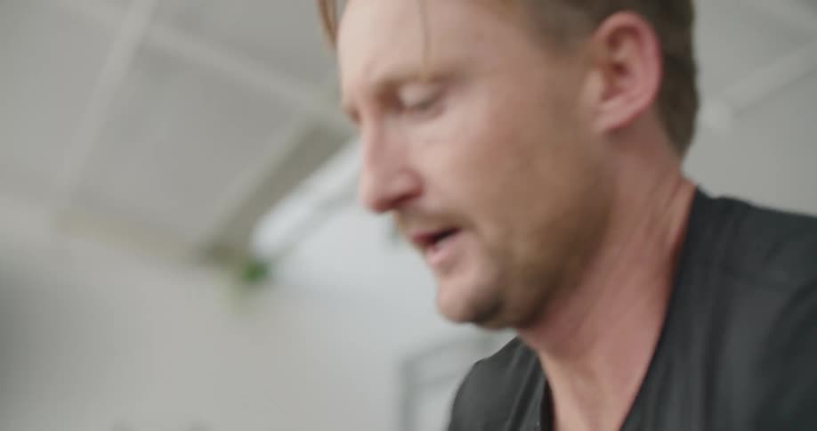 A man exercises strenuously on an exercise bike in a gym during the day