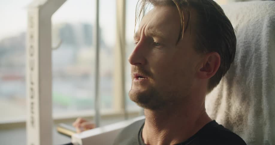 A man is working out indoors next to a window