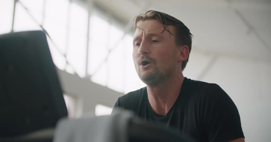A man stops running on the treadmill and checks his watch
