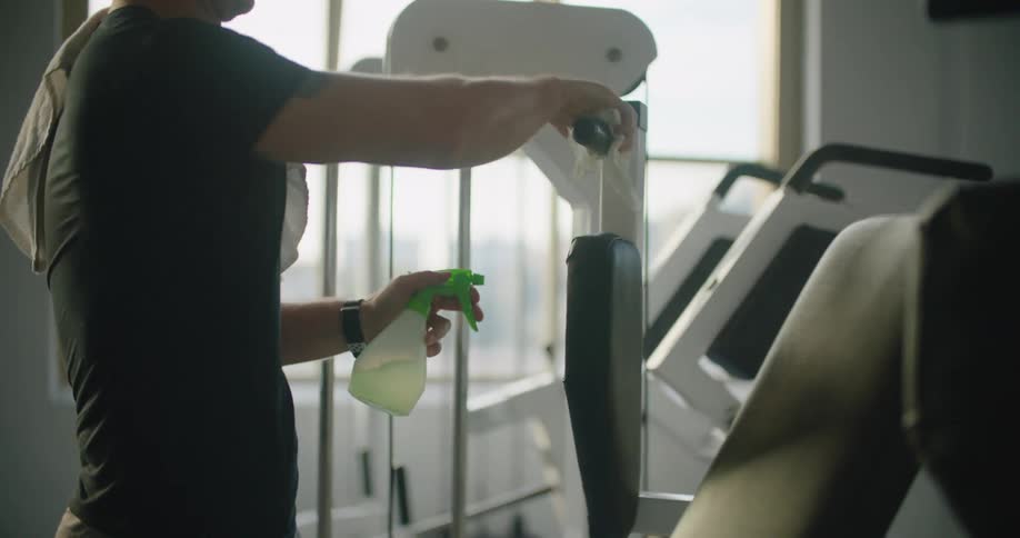 A man is cleaning the equipment in the gym after a workout