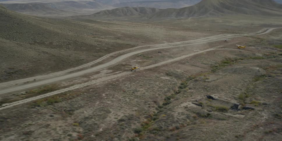 Two small single engine planes on dirt runways