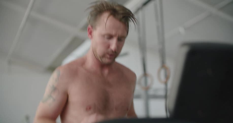 A man adjusts the treadmill as he runs