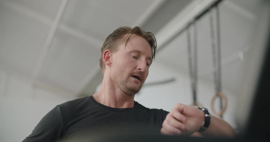A man in a gym standing breathing heavy and sweating
