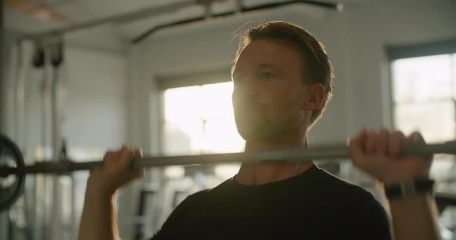 A man is in a gym and lifting weights
