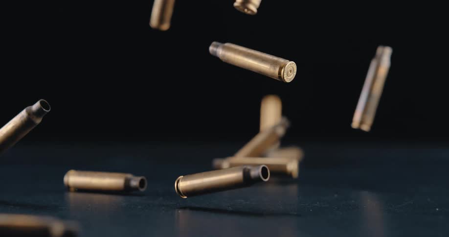 A dozen bullets fall in slow motion onto a flat surface