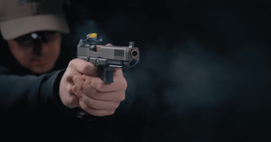 A person with a hat and goggles in a room shooting a gun