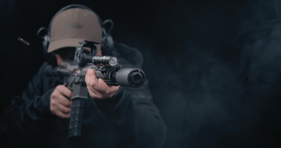 A man fires a rifle in a dark room