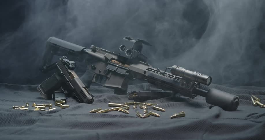Guns and bullets on a black sheet on the floor of a room with smoke