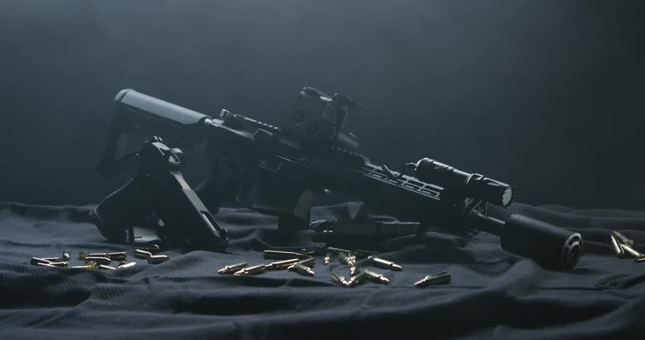 A rifle and gun are on the table surrounded by bullets
