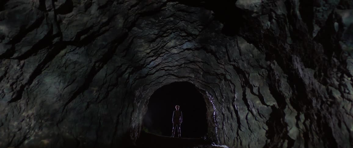 A person stands in a cave while water and light reflect on the rock