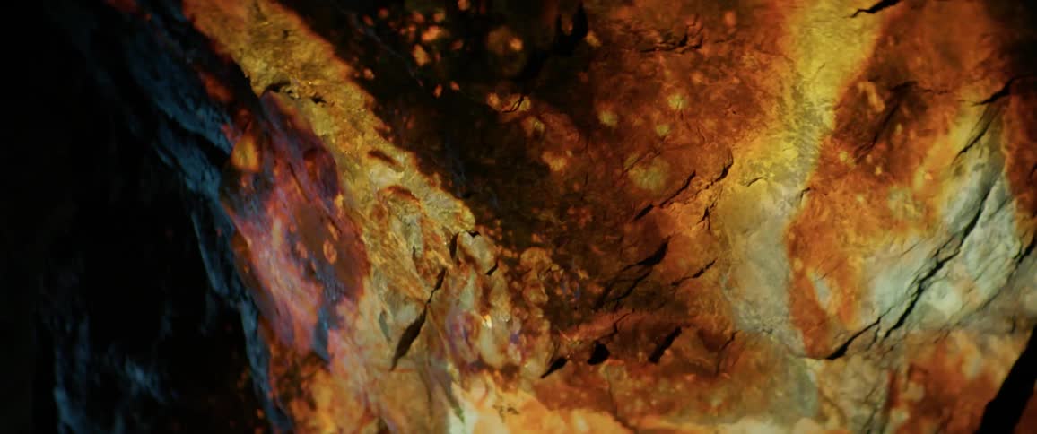 The fire reflects on the wall made of rock