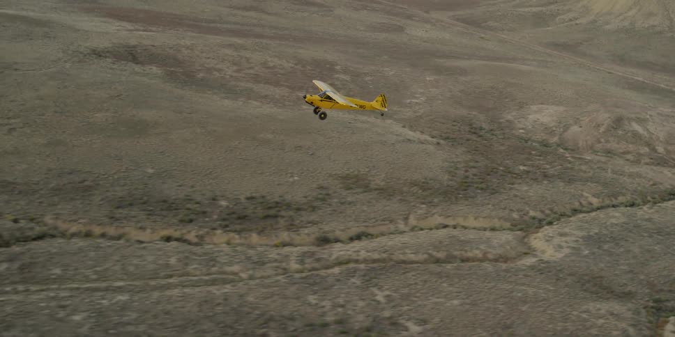 Small yellow plane flying over the countryside