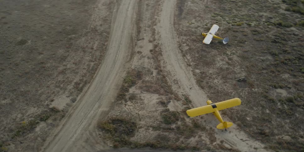 Two airplanes near a dirt path