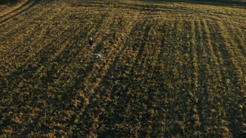 A drone is flying in the air as a child stands in an open field
