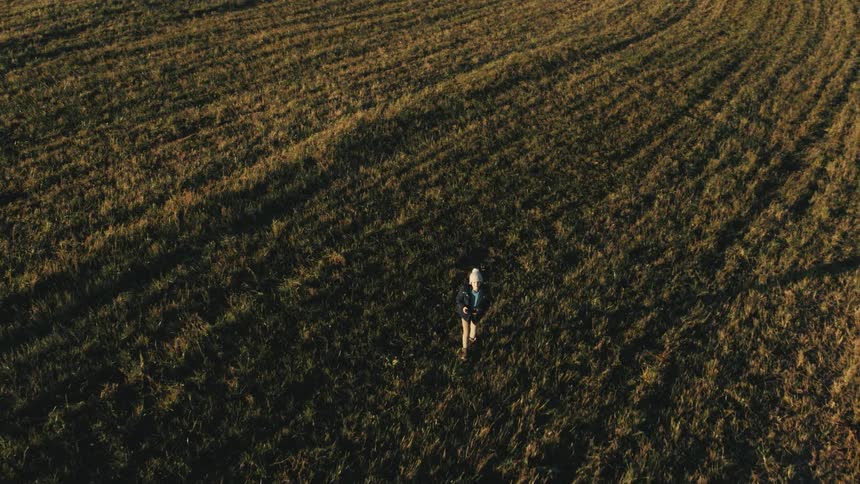 Boy walking on a field at morning flying a drone using a remote control