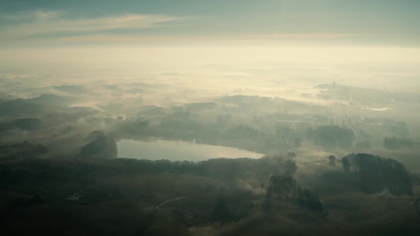 An aerial view of a lake in nature on a foggy day