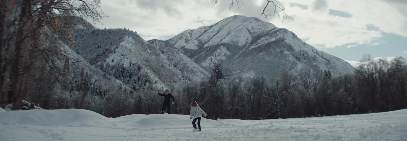 Two small children having a snowball fight in a forest at daytime