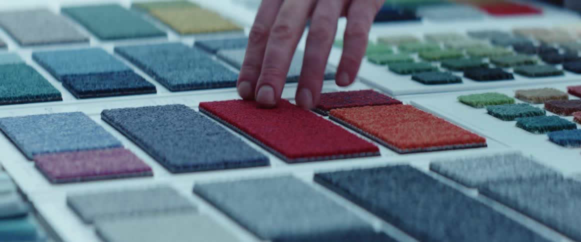 Customer testing carpet samples over a desk in a meeting room