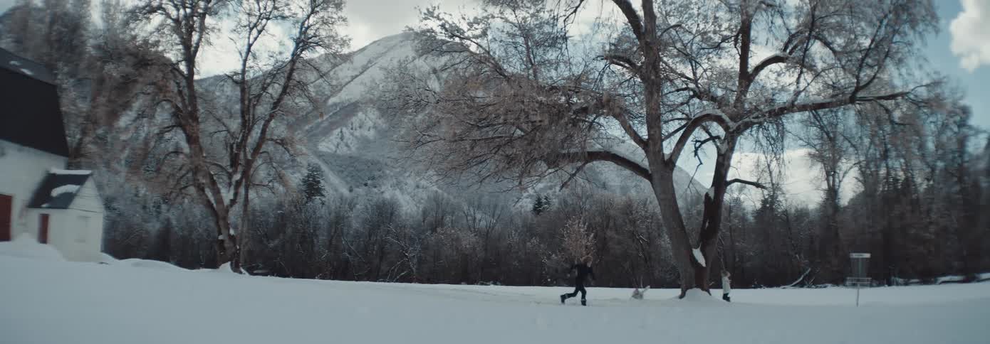 Two young children running around and playing with a dog outside in snow