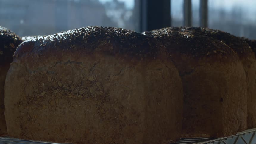 A baker organizing freshly made bread on the shelfs of a shop