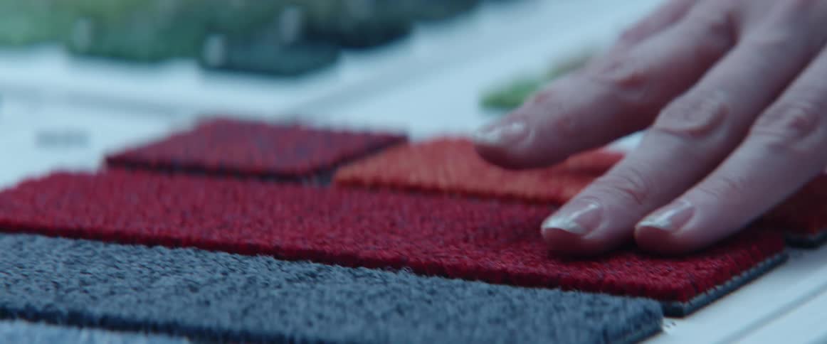 A person touching different fabrics on a table