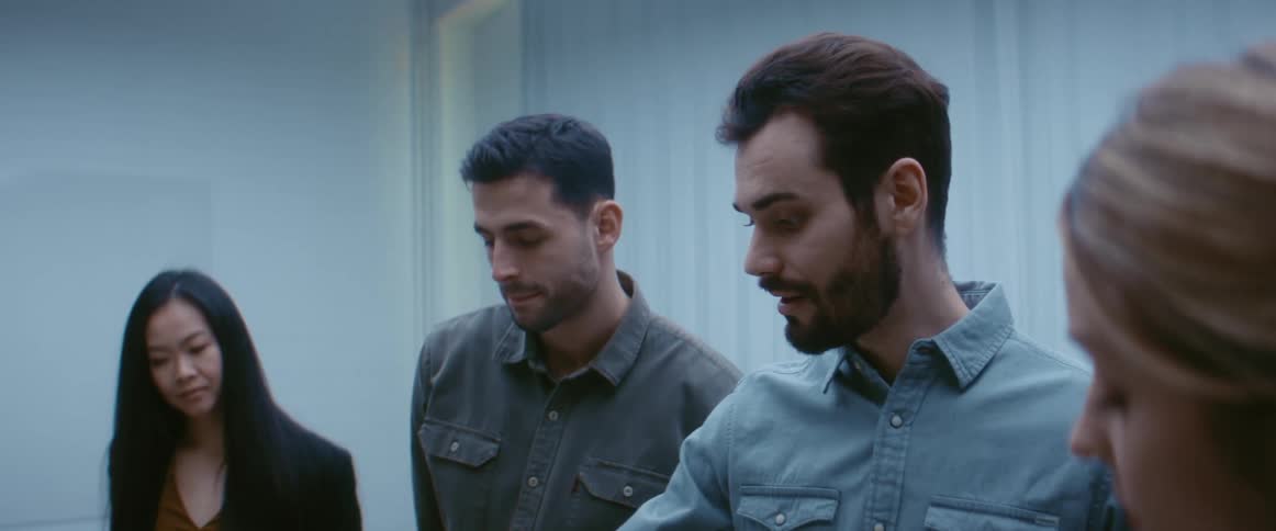 A man in an office talks to another man and two women