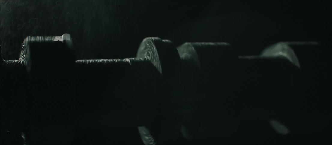 A long piece of metal machinery moving back and forth while being sprayed with with a liquid