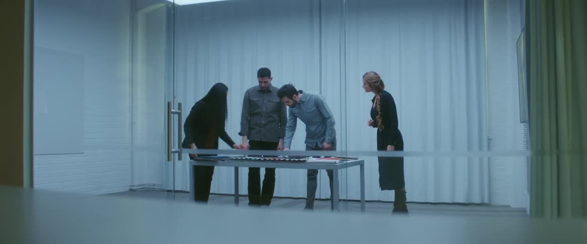 Group of people standing on a meeting room inside an office looking at samples