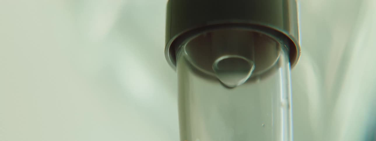 A lab worker watches liquid drip inside an iv before turning it on its side