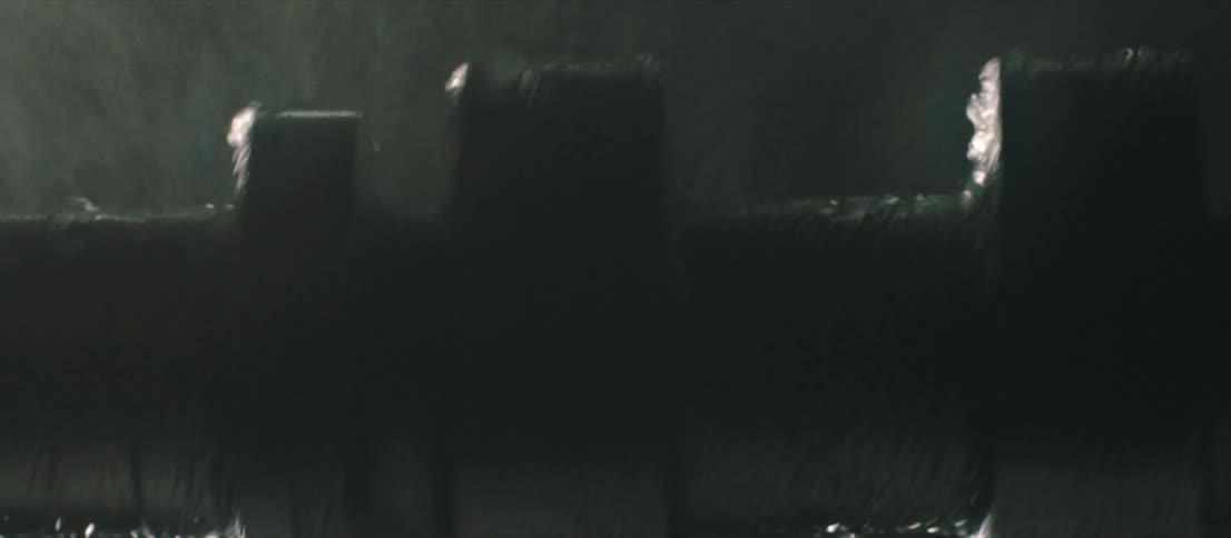 A metal tube rotates while water falls on it and a light flashes