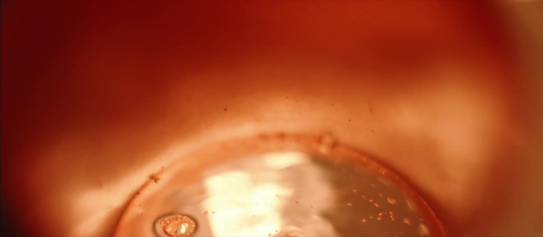 Clear liquid bubbling inside a metallic bowl under flashing colored lights