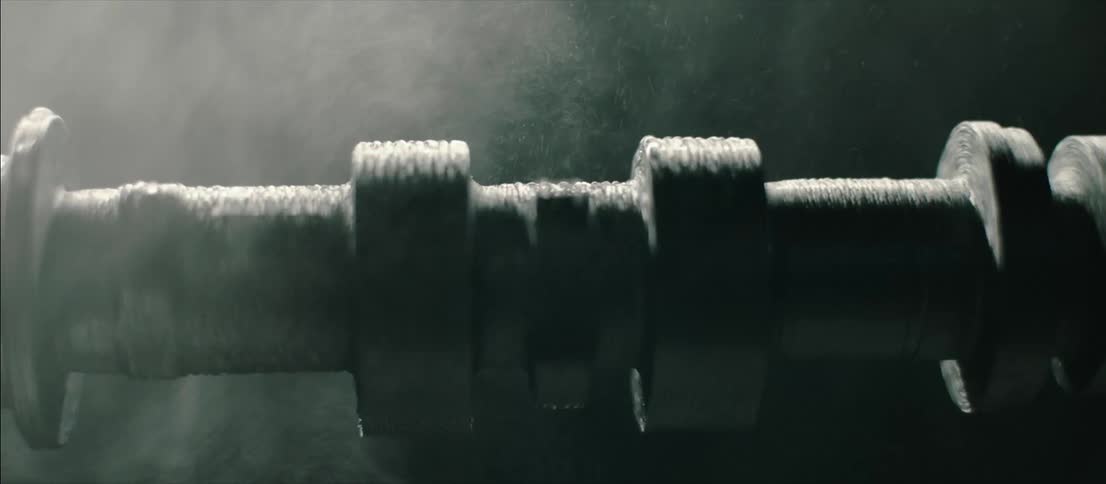 Water sprays on a rotating cylinder agains a black background as light flashes