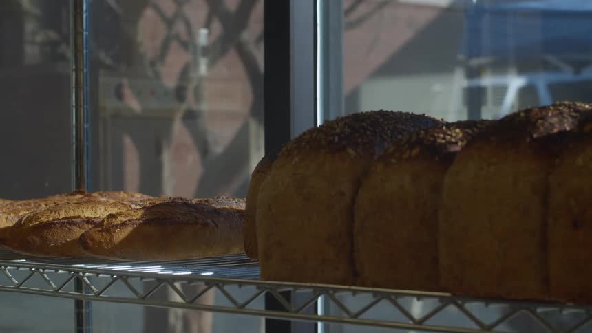 Baker puts bread on the shelf in the bakery