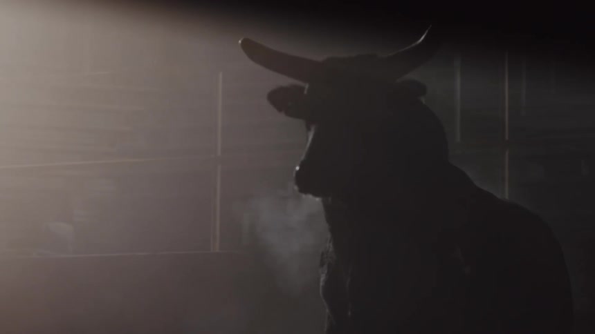 A bull running in an empty dark arena