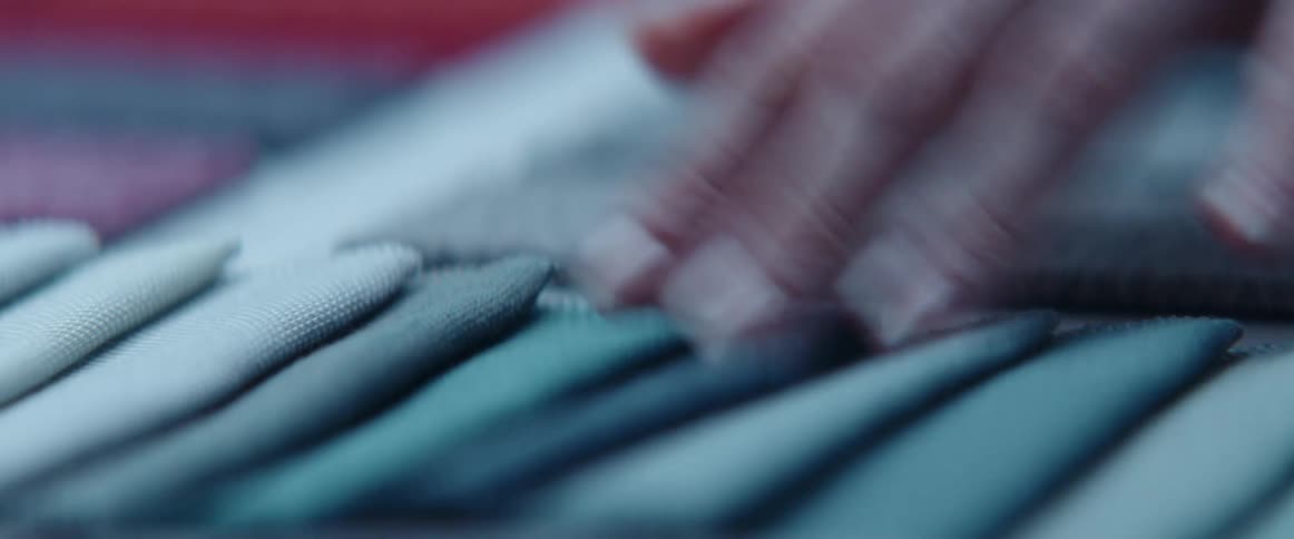 A person is touching the fabric on the table